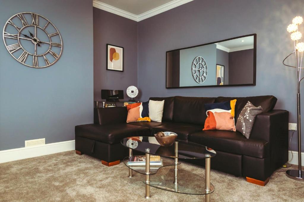 a living room with a black couch and a clock at Stylish, central, adults-only 1-bed Hideaway in Eastbourne