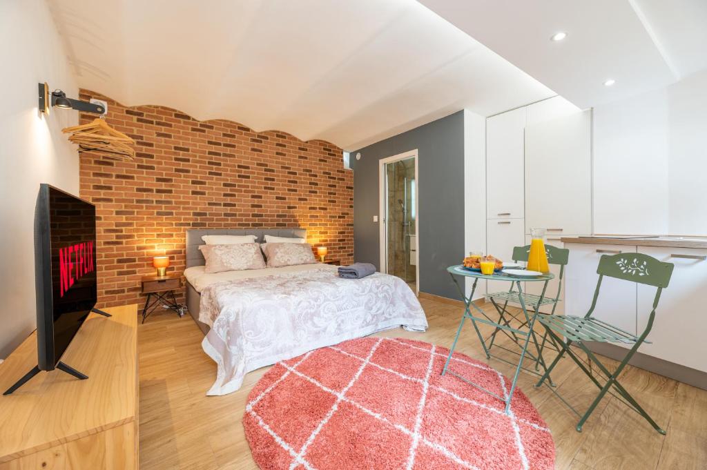 a bedroom with a bed and a brick wall at CHARMANT STUDIO RENOVÉ 150m DE MONACO in Beausoleil