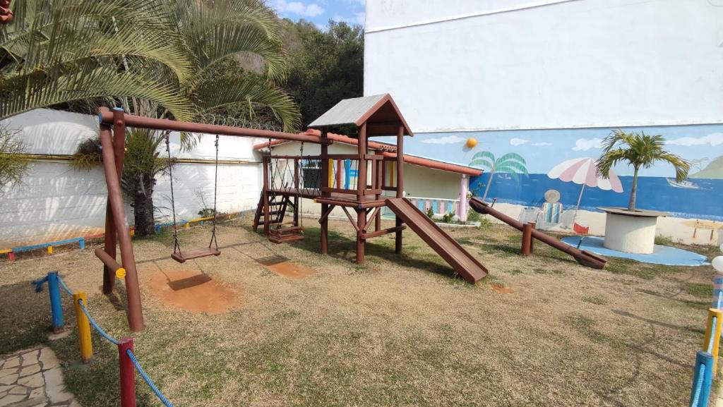 a playground with a wooden swing set in front of a building at Cantinho Por do Sol in Arraial do Cabo