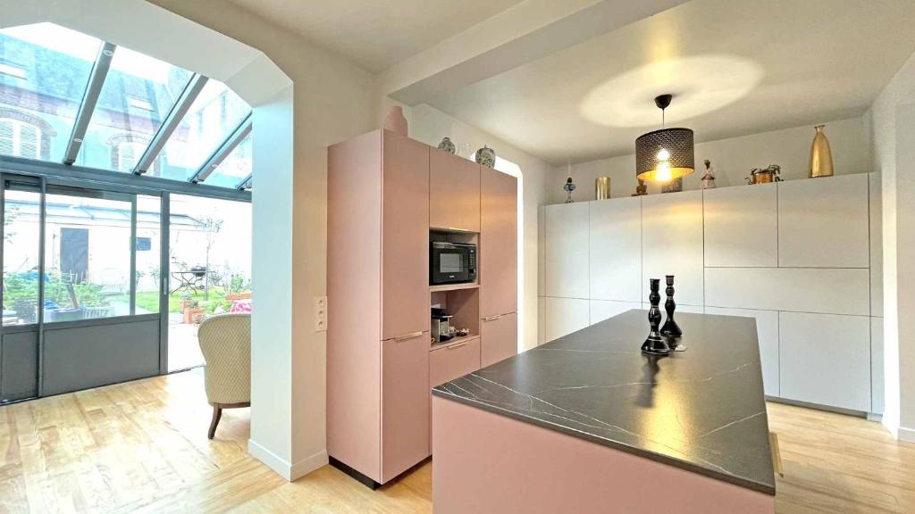 ヴィレ・シュル・メールにあるVilla Renéのピンクと白のキャビネットとテーブル付きのキッチン