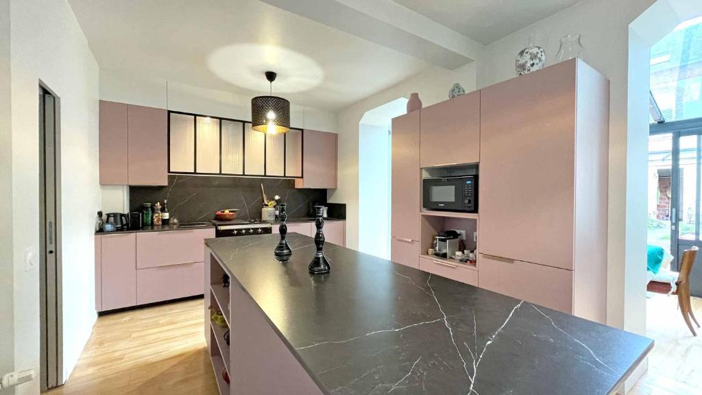 ヴィレ・シュル・メールにあるVilla Renéのピンクのキャビネットと黒のカウンタートップが備わるキッチン