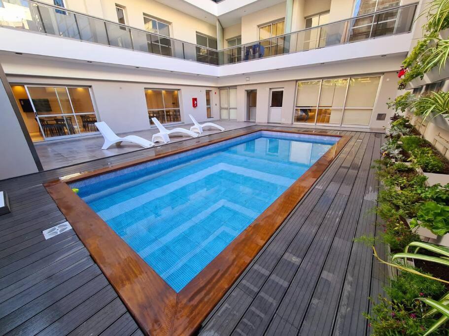 una piscina con terraza de madera y un edificio en Dpto Nva Cba, pileta seguridad, cochera en Córdoba