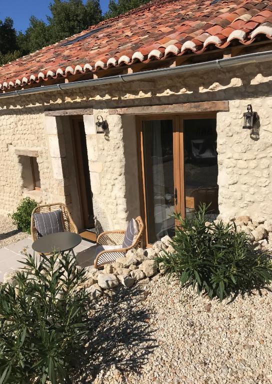 une maison en pierre avec une table et des chaises à l'extérieur dans l'établissement Les Ombrieres, à Porcheresse