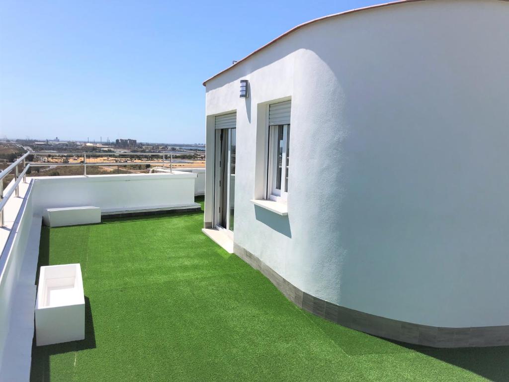 a balcony of a white house with green grass at Luxury Attics Plaza Punto PARKING INCLUIDO in Huelva