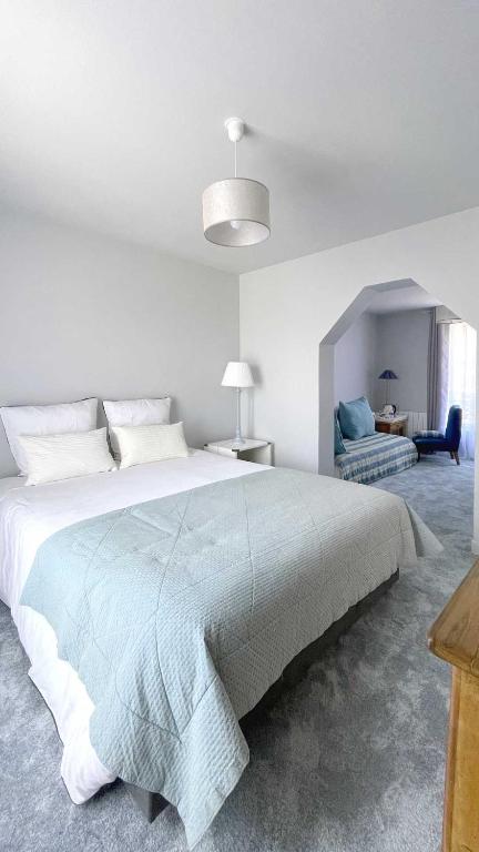 une chambre blanche avec un grand lit et une chaise dans l'établissement Villa René, à Villers-sur-Mer