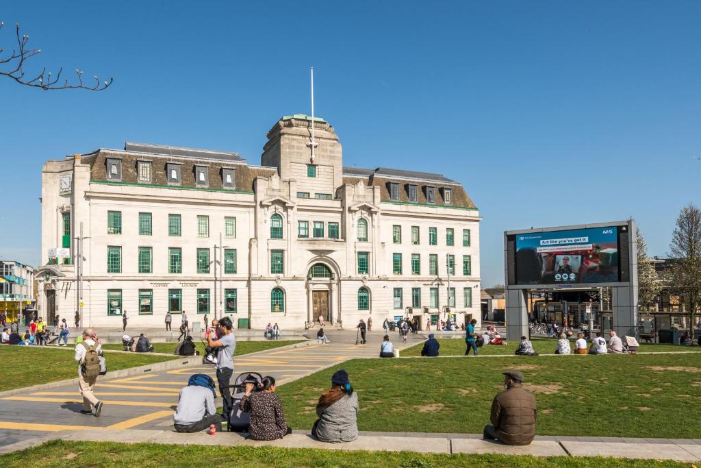 een groep mensen die voor een gebouw zitten bij Equitable Hotel in Woolwich