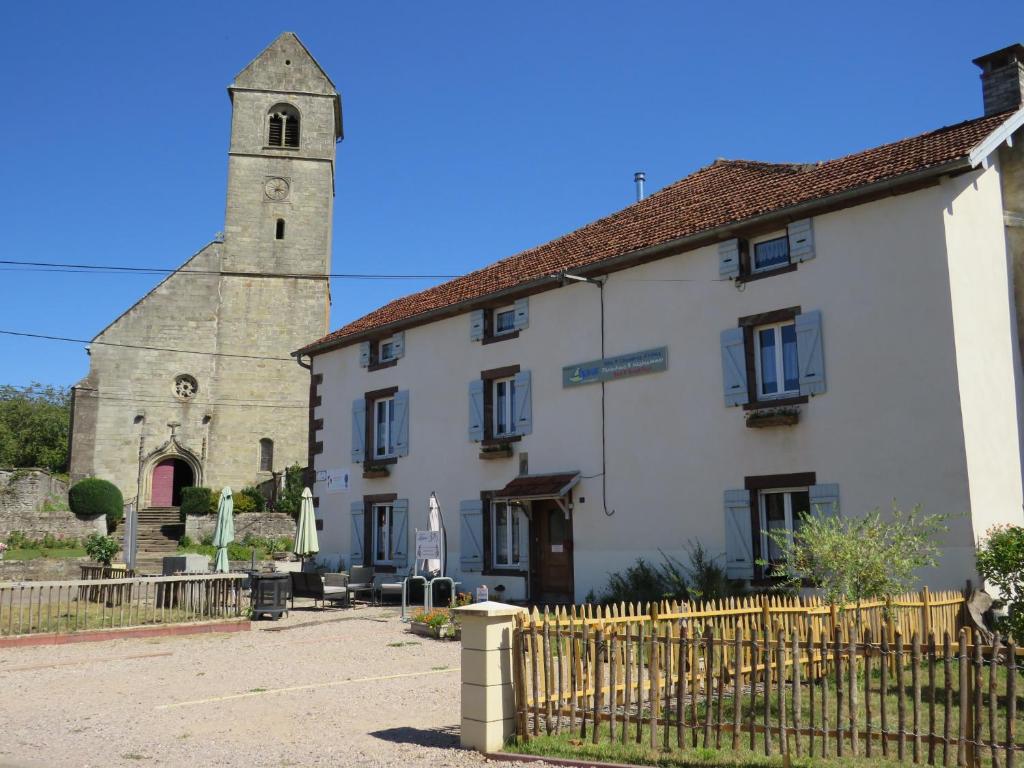 a large white building with a church in the background at Grange d'Anjeux Bed & Breakfast in Anjeux