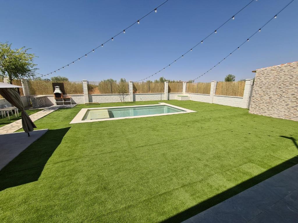 un patio con piscina y césped en Casa Rural Kentia, en Valdepeñas