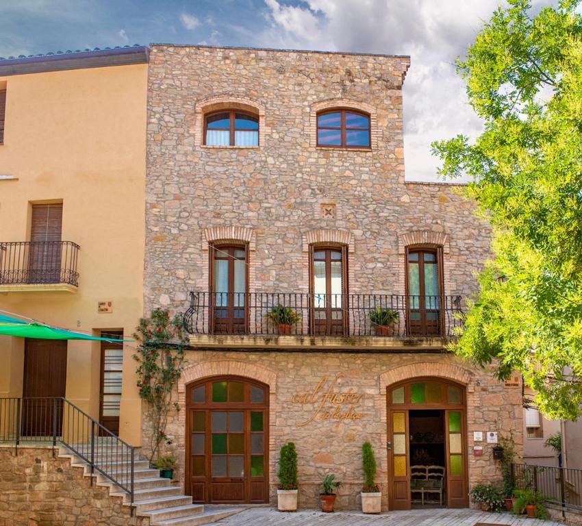 un gran edificio de ladrillo con ventanas y balcones en Cal Fuster De La Plaça, en Sant Martí de Tous