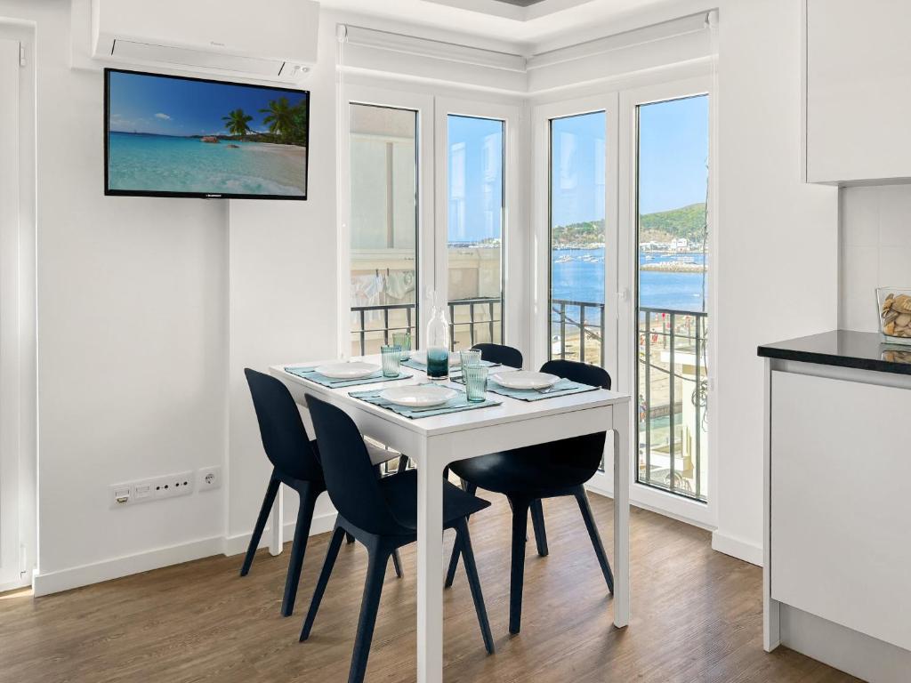 a white dining room with a white table and chairs at Sea Light Apartment Sesimbra. 2 bedrooms, 6 guests in Sesimbra