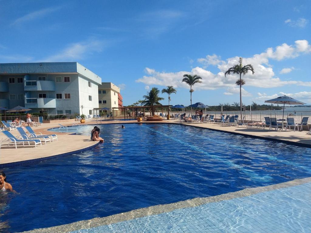 een zwembad in een resort waar mensen zwemmen bij Apartamento no Golden Lake - pé na areia, agua de côco e cervejinha in Arraial do Cabo