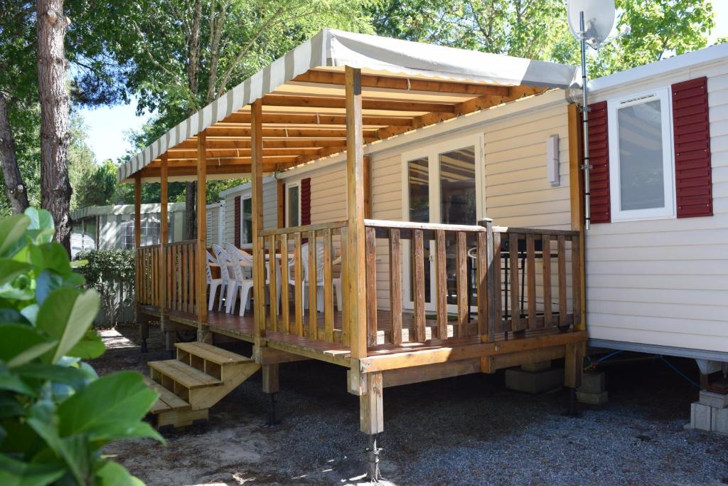 Cette grande cabane en bois dispose d'une terrasse couverte et d'escaliers. dans l'établissement Mobilhome 526 3ch/2SDB camping 4* La Réserve SIBLU Gastes, à Gastes