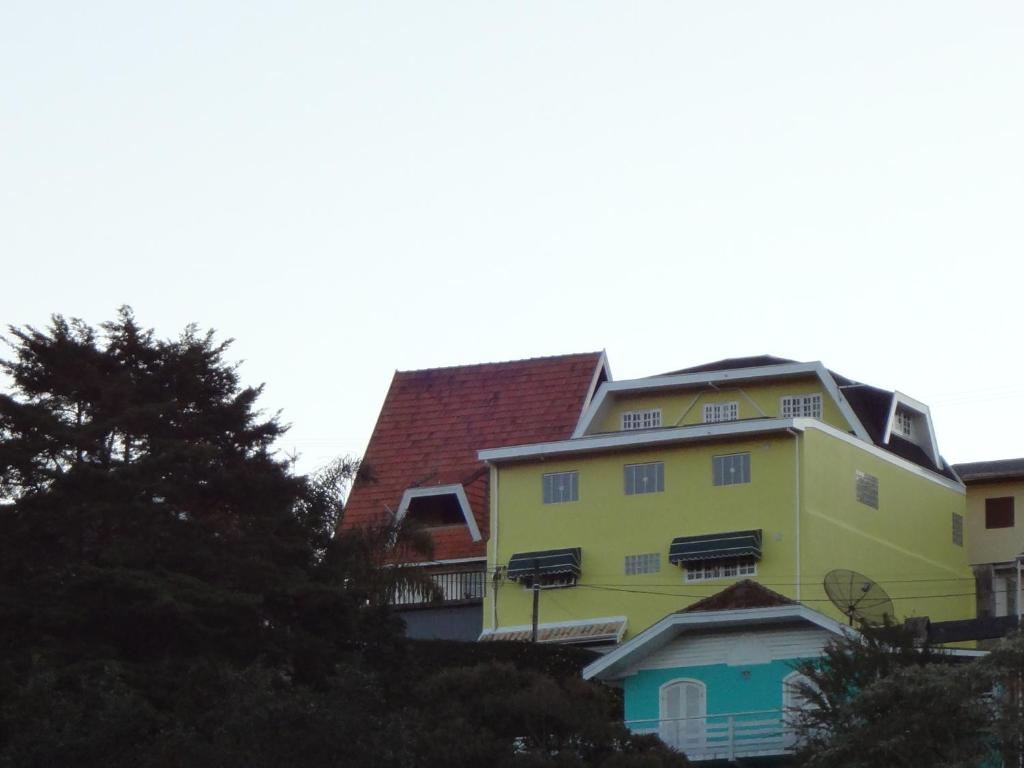 una casa amarilla con techo rojo en Residência Tia Stella, en Campos do Jordão