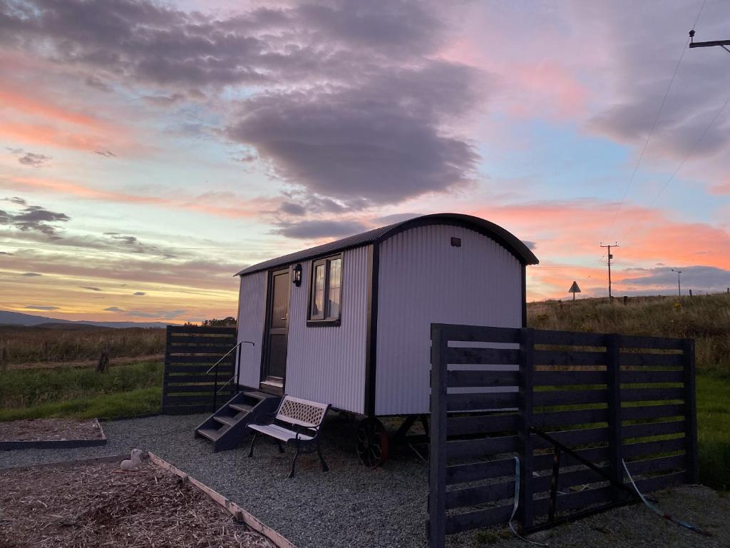 a small shed with a bench and a chair in a field at Shepherds Hut in Lonmore