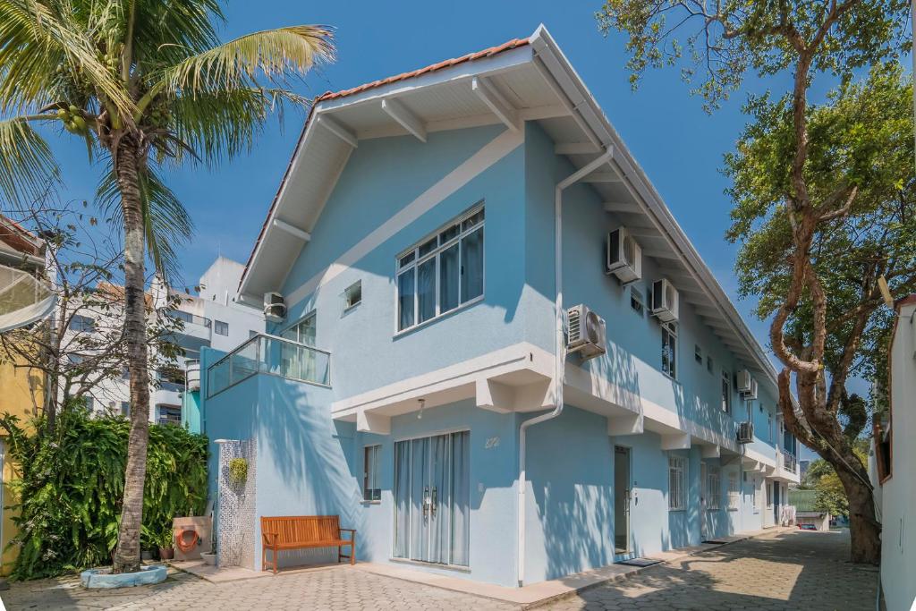 a blue and white building with palm trees at Residencial Bombinhas in Bombinhas