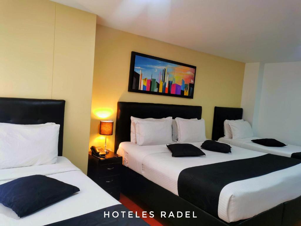 a hotel room with two beds and a painting on the wall at Hotel Radel Superior in Bogotá