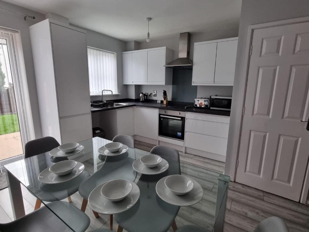 a kitchen with a table and chairs and a kitchen with white cabinets at Beautiful 4 bed home, Sleeps 8, driveway parking, With sky & BT sports in Manchester