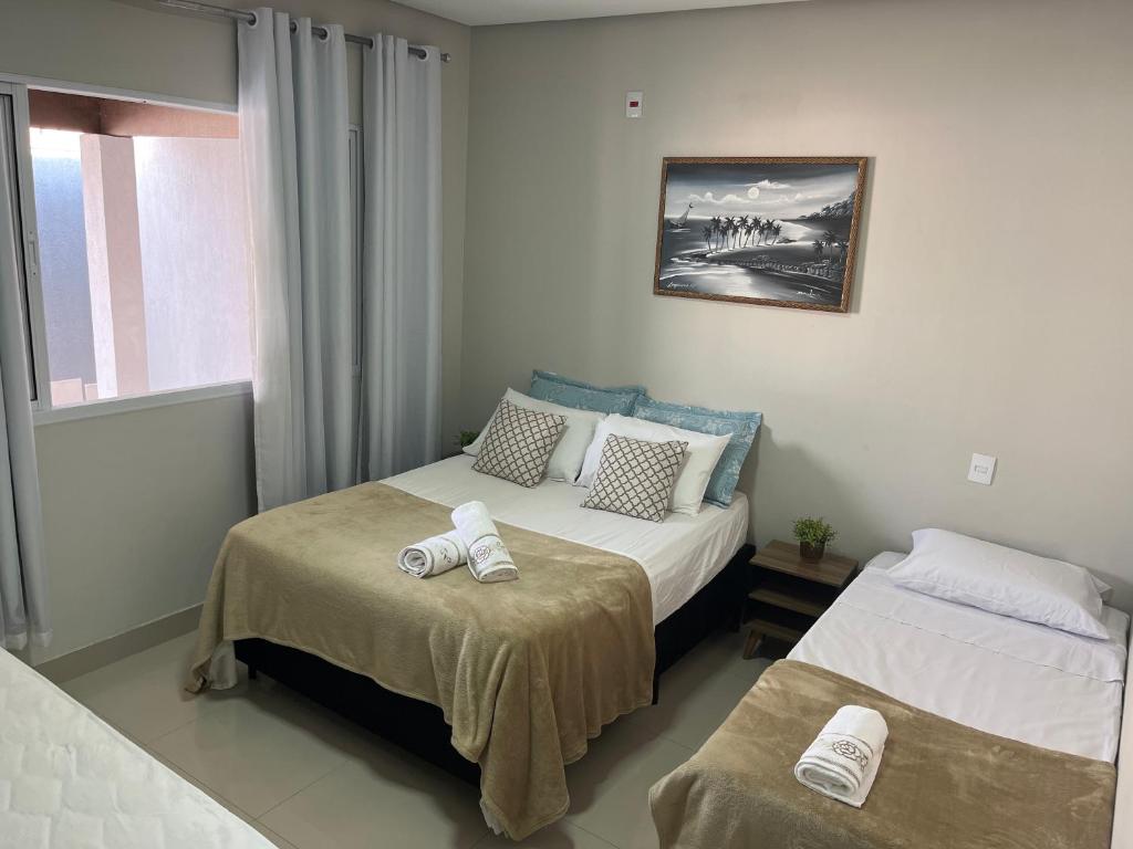 ein Hotelzimmer mit 2 Betten und einem Fenster in der Unterkunft Casa Família Paraíso in Capitólio