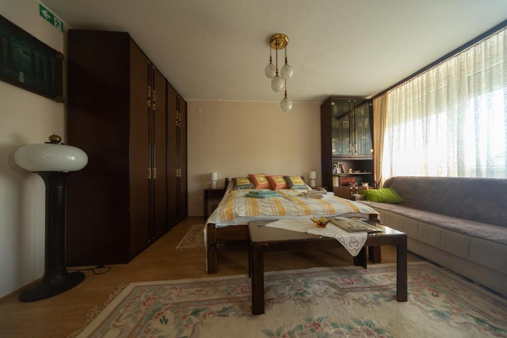 a bedroom with a bed and a couch and a table at Suflat Apartman Studio in Subotica