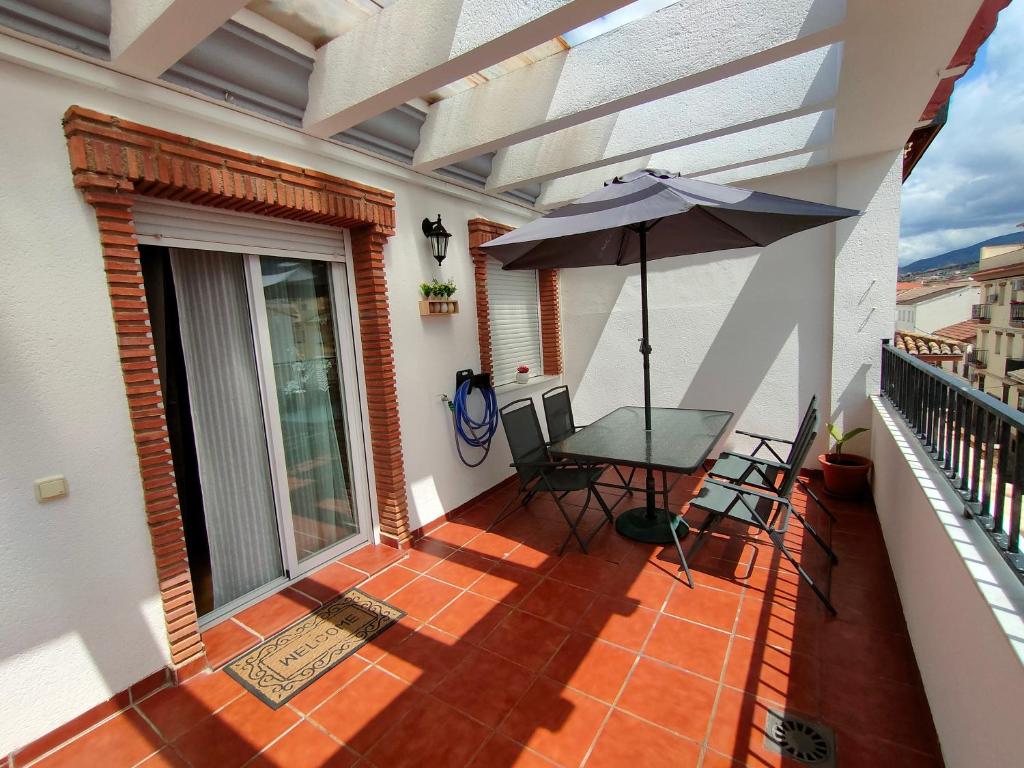 - un balcon avec un parasol, une table et des chaises dans l'établissement Ático Granada al Sol (terraza vistas montaña), à La Zubia