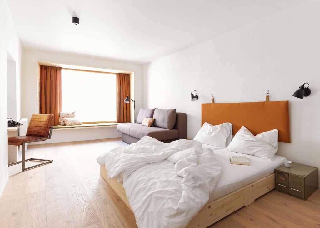 a bedroom with a large bed and a couch at Urban Inn - Wilten 24/7 in Innsbruck