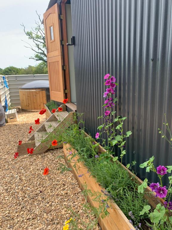einen Garten mit Blumen neben einem Zaun in der Unterkunft Shepherds Hut with Scandinavian Hot Tub and hydromassager in Sway