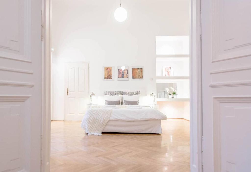 um quarto branco com uma cama e piso em madeira em Bourgeois Elegance in the heart of Budapest em Budapeste