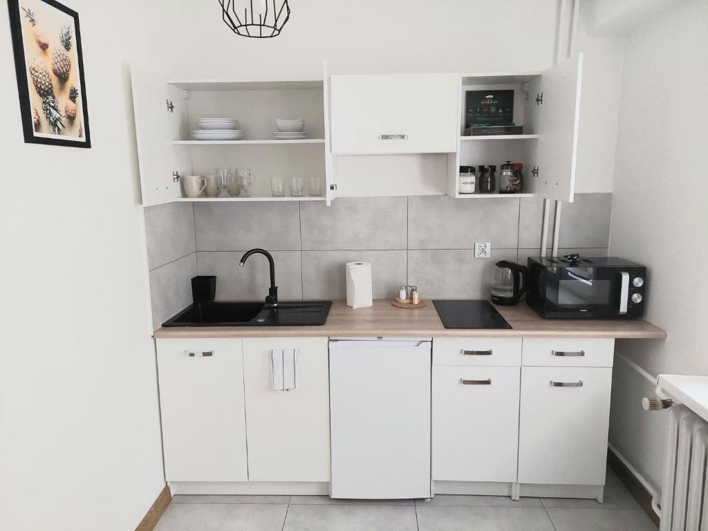 uma cozinha com armários brancos, um lavatório e um micro-ondas em Apartament na Reja em Olkusz