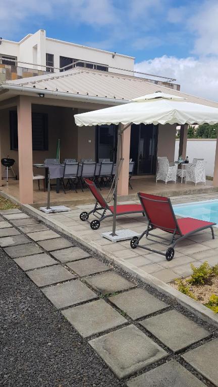 dom z basenem, krzesłami i parasolem w obiekcie Villa Le Mahé w mieście Beau Vallon