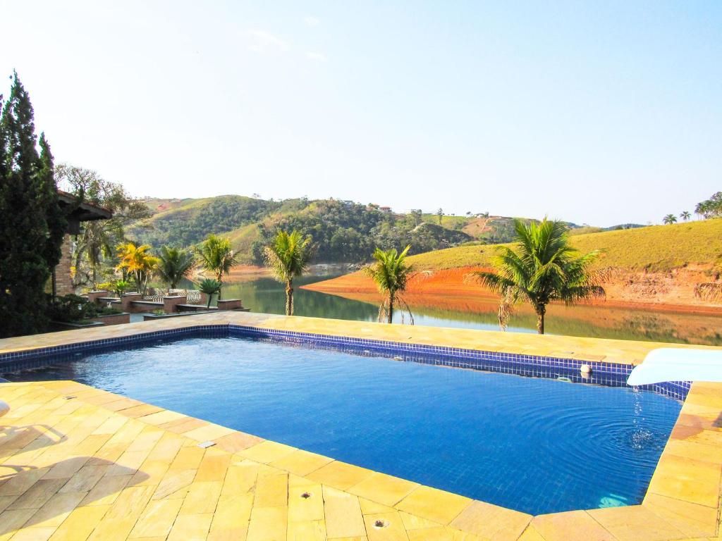una piscina con vistas al río y a las palmeras en Lindo Sitio na beira da represa em Santa Isabel - SP, en Igaratá