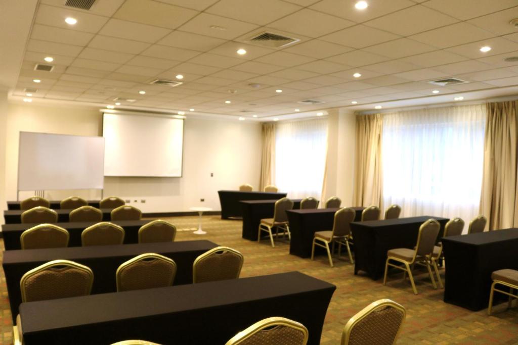 a conference room with tables and chairs and a screen at Ecohotel Talca in Talca