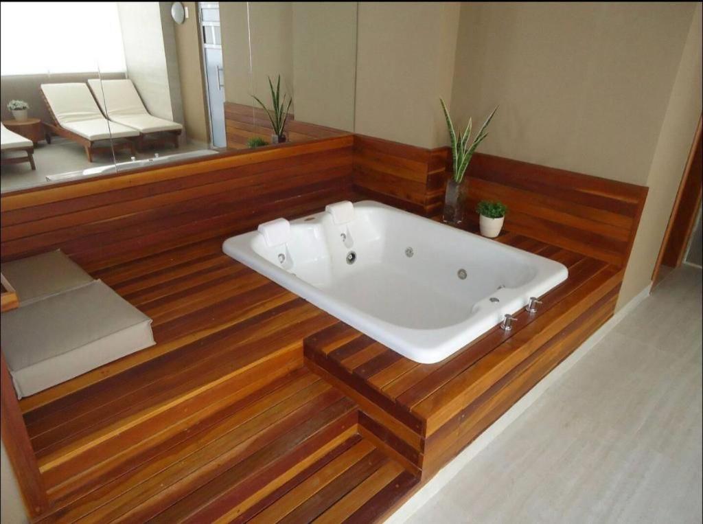 uma banheira num quarto com piso em madeira em FlatsRose BR Executivo BrookField Flamboyant Conforto Top em Goiânia