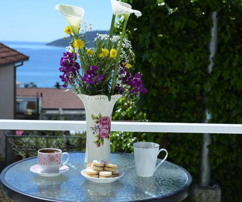 a table with a vase and two cups of coffee at Apartments Vlaovic in Herceg-Novi