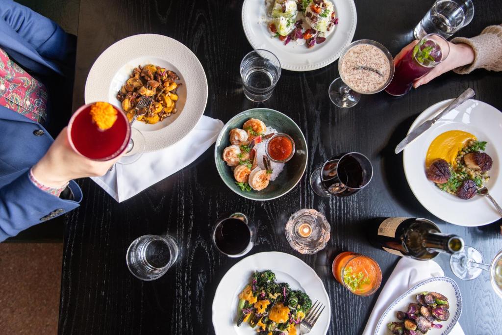 a table with plates of food and glasses of wine at Fordson Hotel, in the Unbound Collection by Hyatt in Oklahoma City