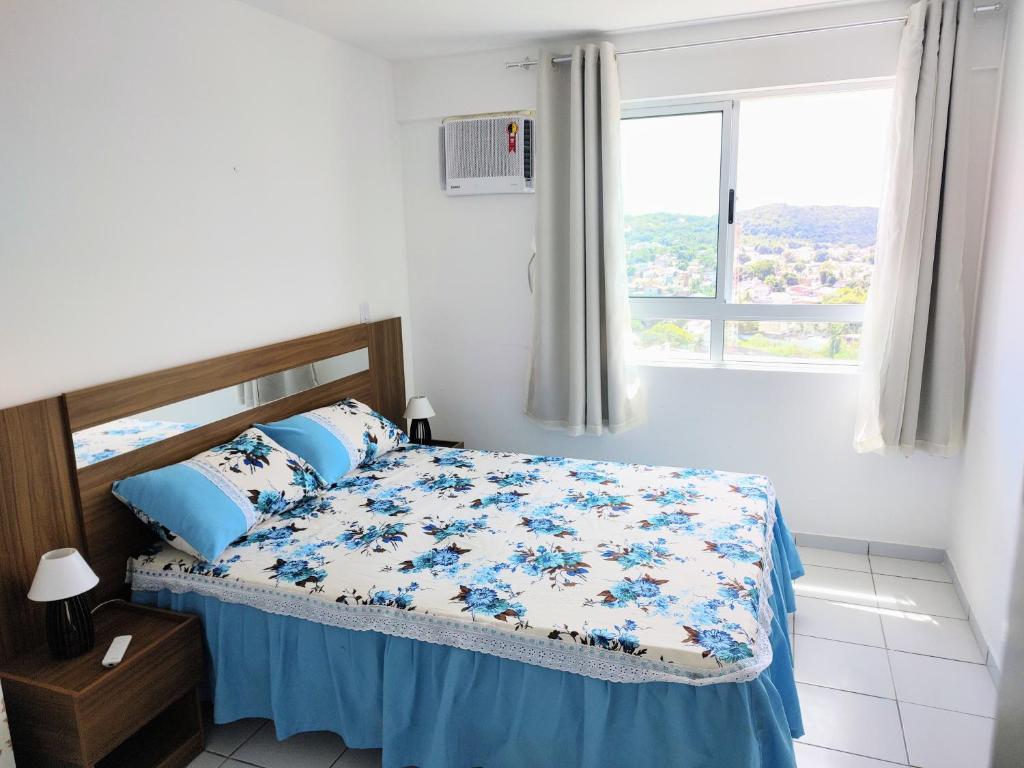 a bedroom with a bed with blue and white sheets and a window at Apartamento completo/ Verano Ponta Negra- Natal in Natal