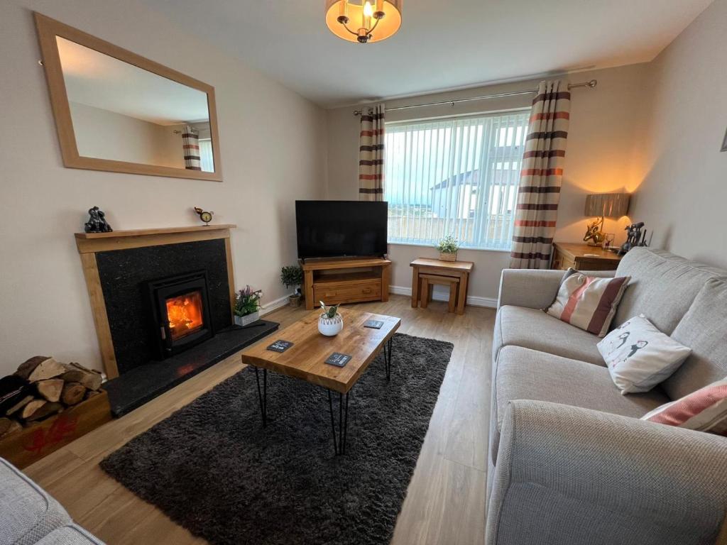 a living room with a couch and a fireplace at Two bedroom house with enclosed gardens and 2 car drive in Caeʼr-geiliog