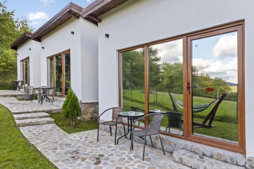 a patio with chairs and a table and windows at Silver Bungalow in Săcele