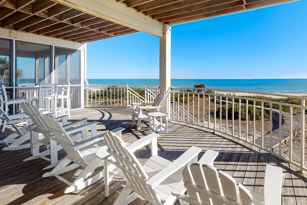 - une terrasse avec des chaises blanches et la plage dans l'établissement Amelia, à Île Saint Georges