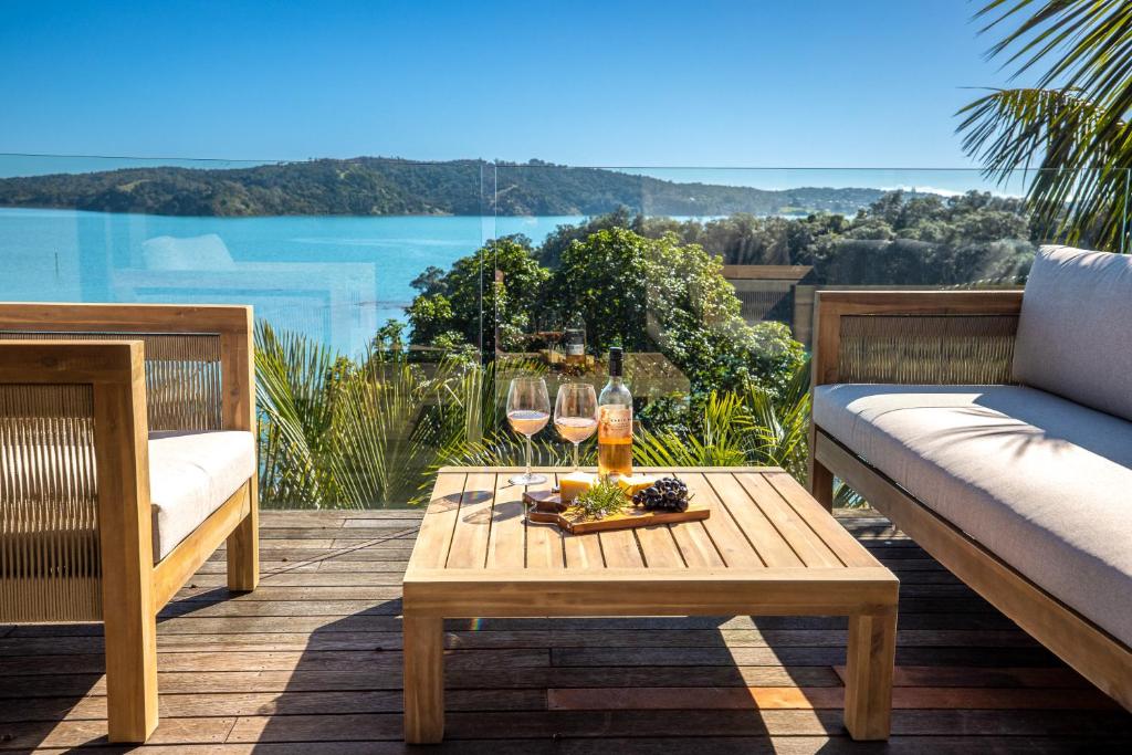 una mesa con copas de vino y botellas de vino en el patio en Palms on Kennedy Point, en Te Whau Bay
