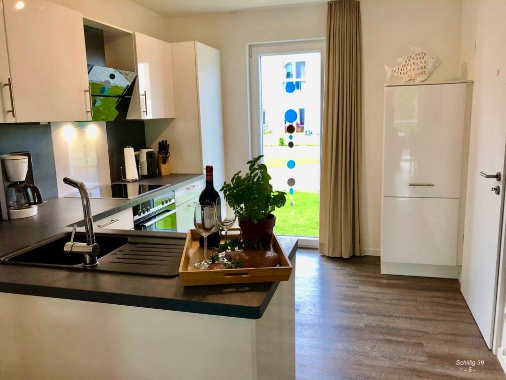 eine Küche mit einem Waschbecken und einer Theke mit einer Flasche Wein in der Unterkunft Familienhaus an der Nordsee - Sauna - Kamin - Südterrasse direkt über dem Wasser in Wangerland