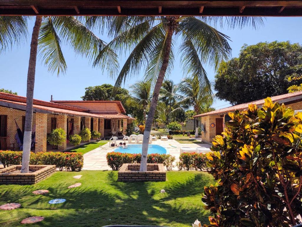 un patio trasero con palmeras y una piscina en Pousada Solar das Fontes, en Beberibe