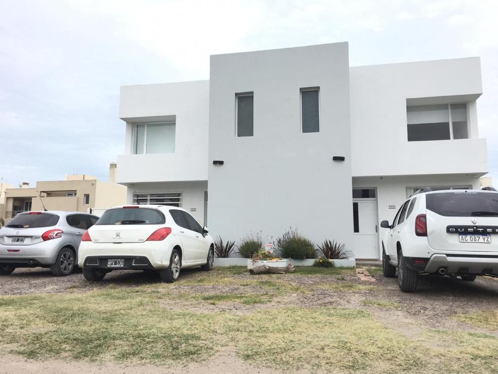 un gruppo di auto parcheggiate di fronte a un edificio bianco di COMPLEJO LAVANDAS a Balneario El Cóndor