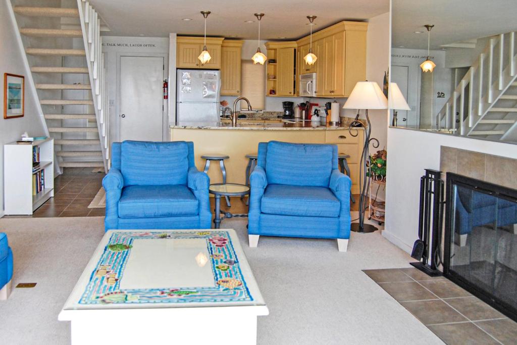 a living room with two blue chairs and a fireplace at Great Lakes 49 50 in Glen Arbor