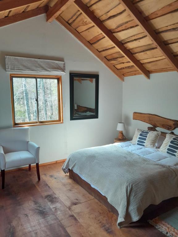 1 dormitorio con 1 cama, 1 silla y 1 ventana en Refugio369cl - LodgeTenisPuconcl, en Pucón