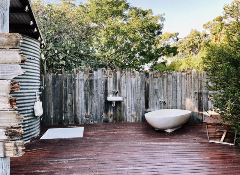 a bath tub sitting on a deck next to a fence at Luxury 6 metre Bell Tent & Outdoor Bathroom, WIFI, TV and firepit, in Coodanup
