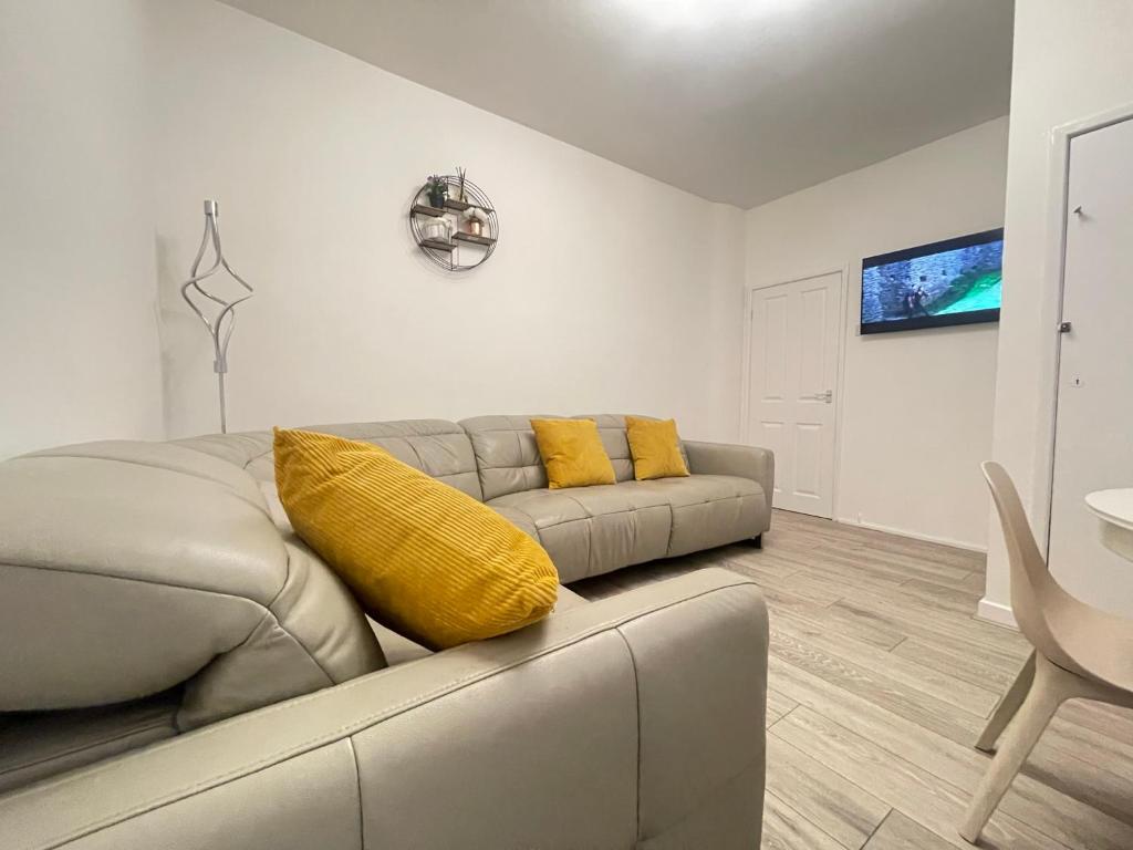 a living room with a gray couch and yellow pillows at Coast View Professional Let in Whitley Bay