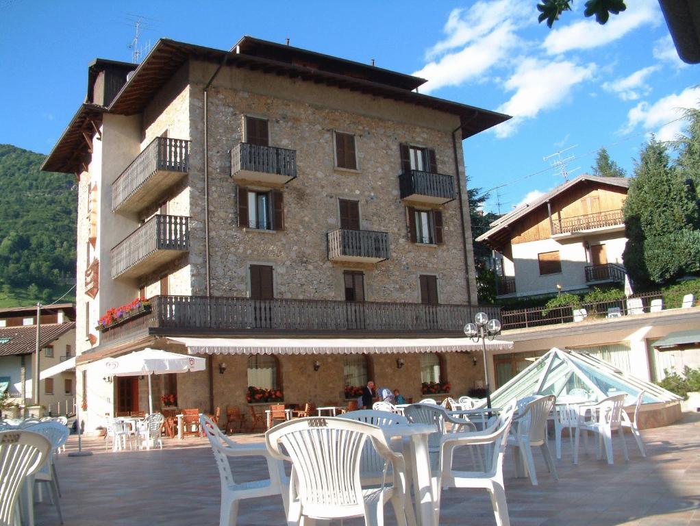 a building with tables and white chairs in front of it at Hotel Carrara in Serina