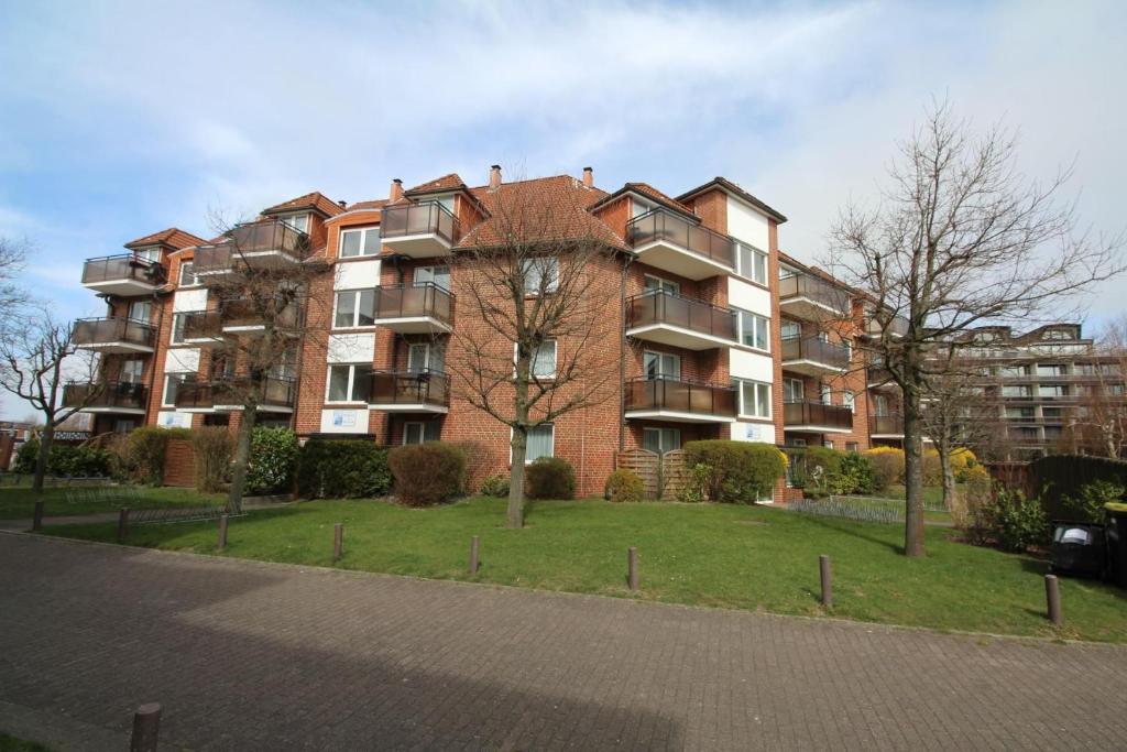 um grande edifício de apartamentos em tijolo com um parque em frente em Residenz Passat Cuxhaven 4 em Cuxhaven