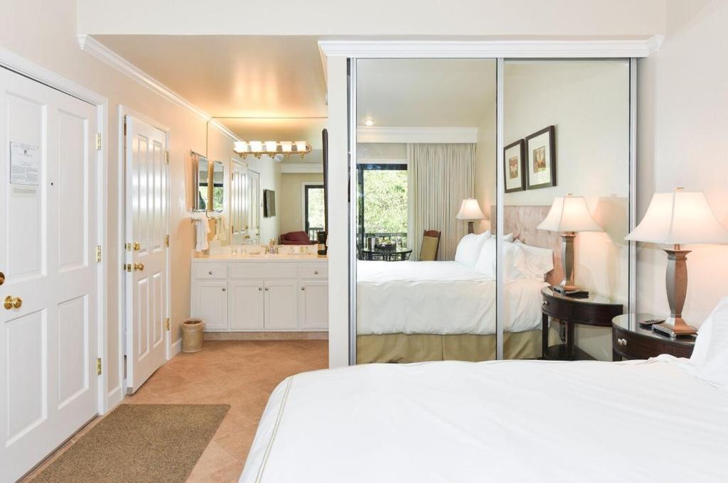 a bedroom with two beds and a bathroom with a mirror at 703 Cottages at Silverado residence in Napa