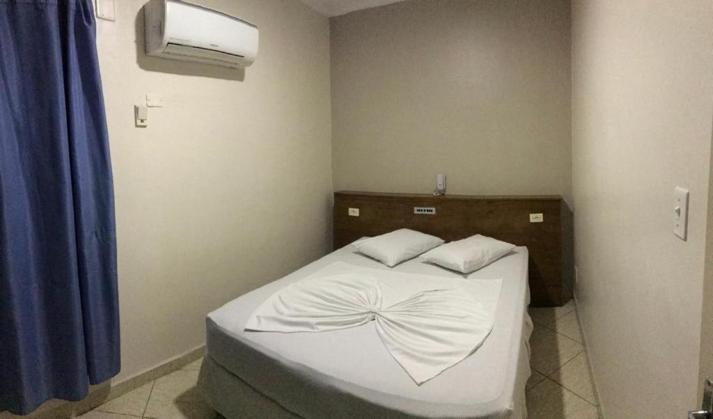 a small bedroom with a bed with white sheets at Casarão Hotel in Santos
